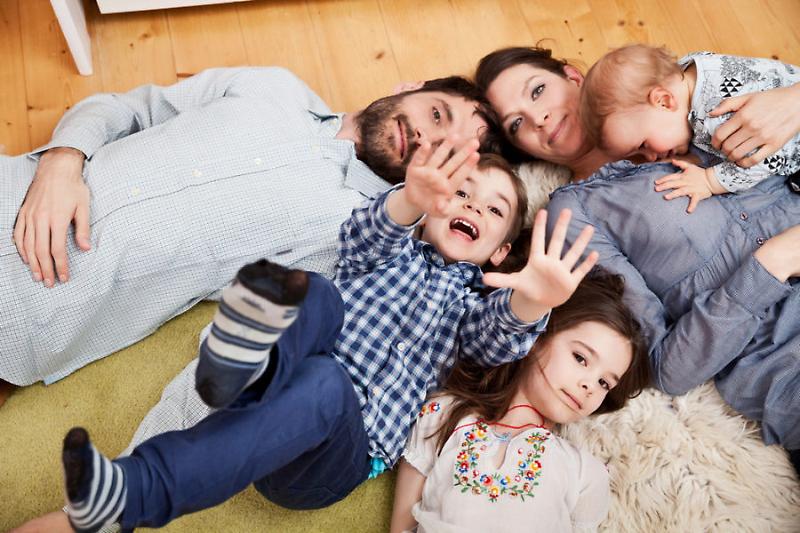 Family of five laying on the ground, looking at camera